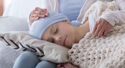 Caregiver supporting sleeping sick child with cancer in the hospice