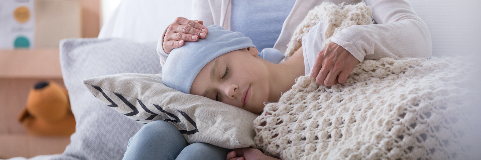 Caregiver supporting sleeping sick child with cancer in the hospice