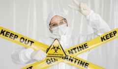 epidemiologist woman in protective clothing is in a restricted area with a danger sign. yellow line keep out quarantine. quarantine alert sign. entrance is forbidden in quarantine zone