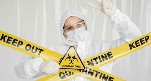 epidemiologist woman in protective clothing is in a restricted area with a danger sign. yellow line keep out quarantine. quarantine alert sign. entrance is forbidden in quarantine zone