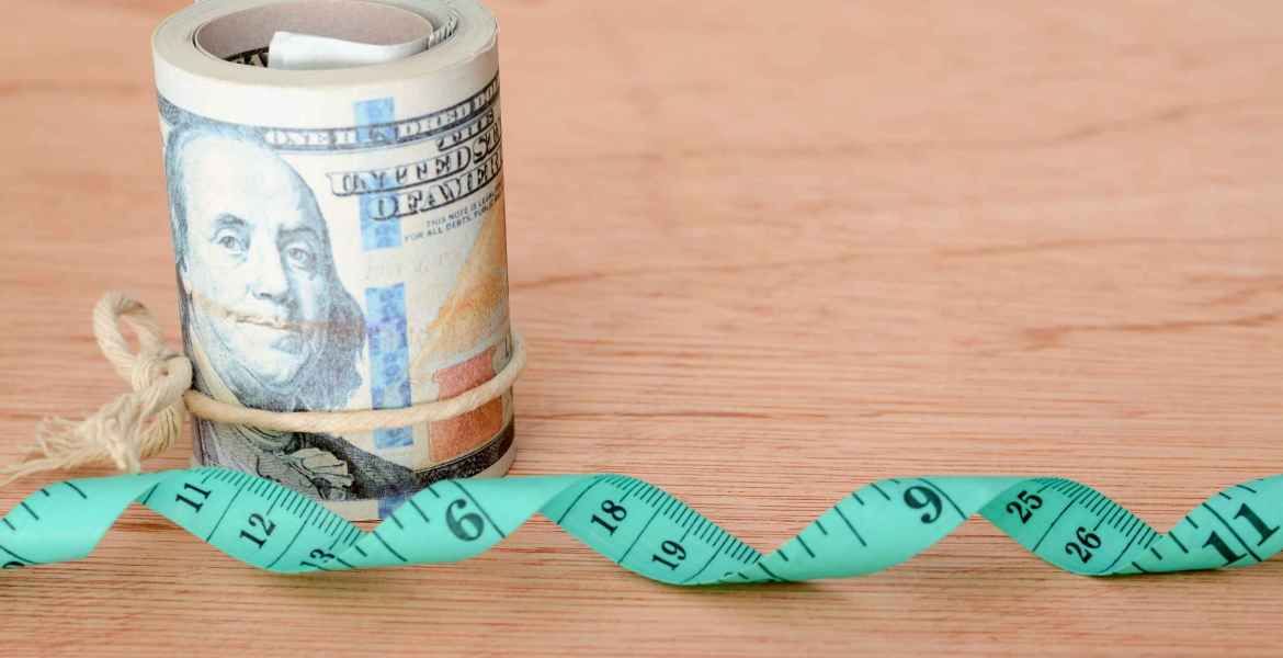 money banknotes and green measuring tape. expense for diet, weight loss and fasting concept