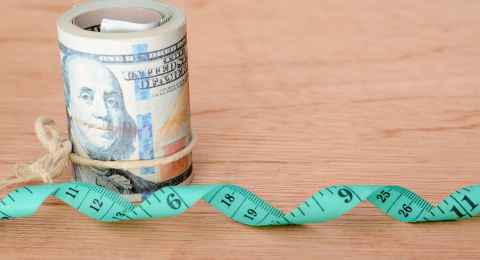 money banknotes and green measuring tape. expense for diet, weight loss and fasting concept