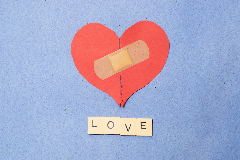 abstract concept of love. broken paper heart with medical health patch.