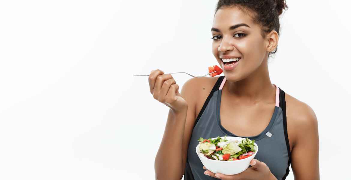 healthy and fitness concept beautiful american african lady in fitness clothes on diet eating fresh salad.