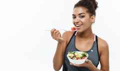 healthy and fitness concept beautiful american african lady in fitness clothes on diet eating fresh salad.