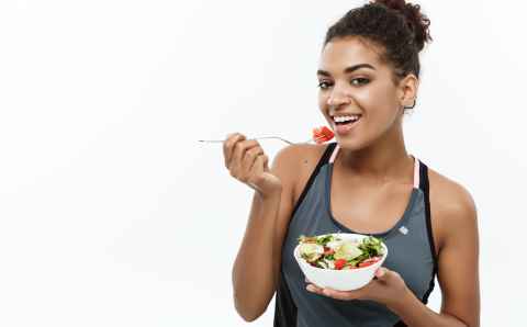 healthy and fitness concept beautiful american african lady in fitness clothes on diet eating fresh salad.