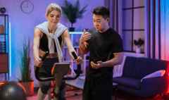 young female wearing sport bra and using exercise bike and her trainer asian male.